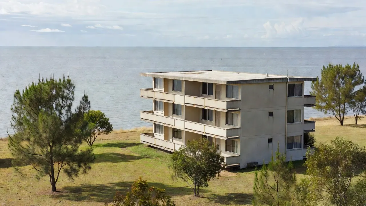 Illustration of a 1970s-style unit block beside the bay, with concrete balconies facing the water.