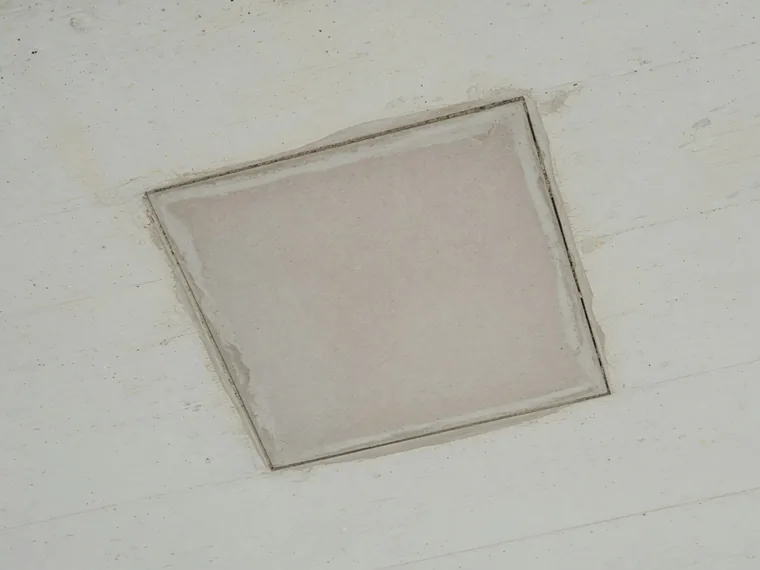 A neat square concrete repair patch cut into a soffit with clean edges and fresh repair mortar.